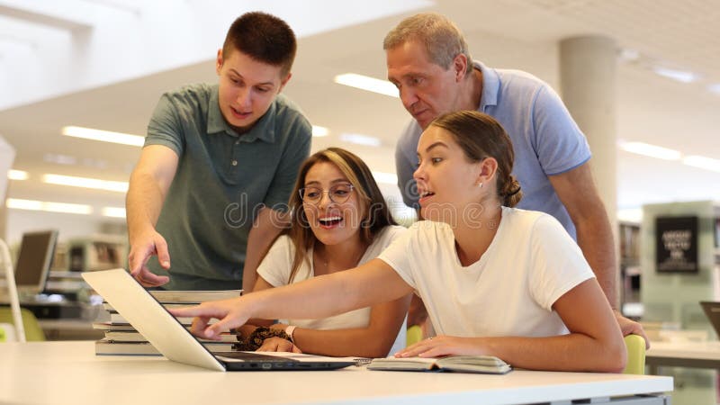 Jonge mannelijke bibliothecaris die advies geeft aan groep personen die op zoek zijn naar informatie over laptop in de bibliotheek