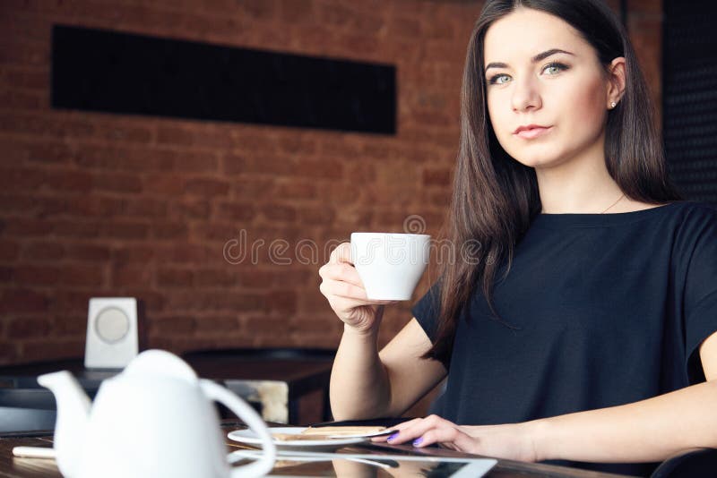 Jonge meisje het drinken thee in koffie en het houden van kop royalty-vrije stock afbeelding Jonge meisje het drinken thee in koffie en het houden van kop royalty-vrije stock afbeelding