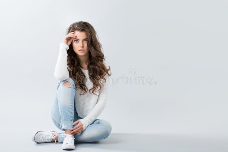Jonge meisjeszitting in jeans en tennisschoenen stock foto Jonge meisjeszitting in jeans en tennisschoenen stock foto
