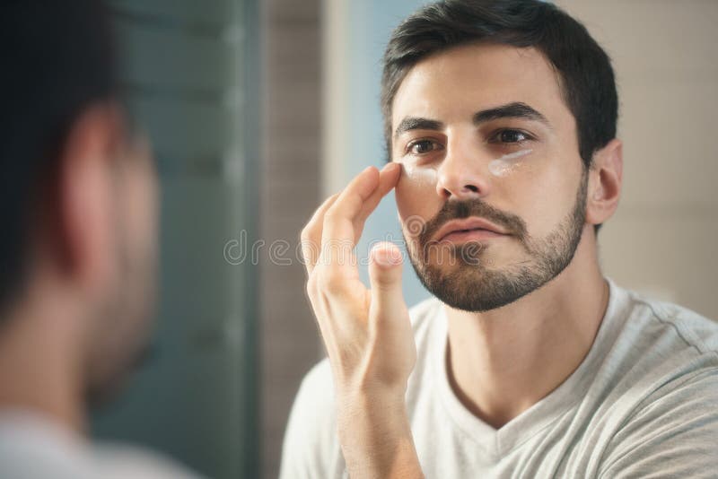 Jonge mens die anti-veroudert de zorg van de lotion fot huid toepassen royalty-vrije stock fotografie Jonge mens die anti-veroudert de zorg van de lotion fot huid toepassen royalty-vrije stock fotografie
