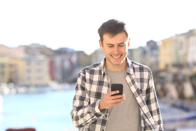 Jonge mens die en slimme telefoon lopen met behulp van stock fotografie Jonge mens die en slimme telefoon lopen met behulp van stock fotografie