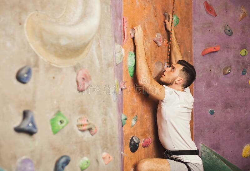 Jonge mens die kunstmatige rotsmuur beklimmen bij gymnastiek stock foto's Jonge mens die kunstmatige rotsmuur beklimmen bij gymnastiek stock foto's