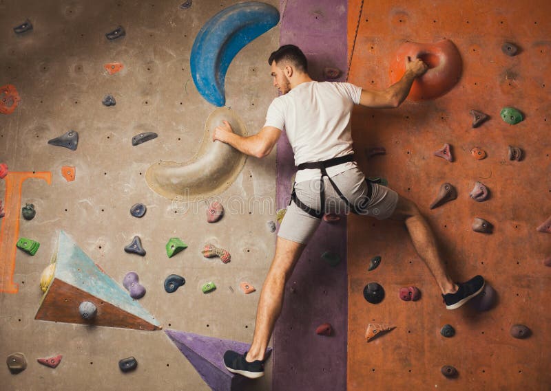 Jonge mens die kunstmatige rotsmuur beklimmen bij gymnastiek royalty-vrije stock afbeeldingen Jonge mens die kunstmatige rotsmuur beklimmen bij gymnastiek royalty-vrije stock afbeeldingen