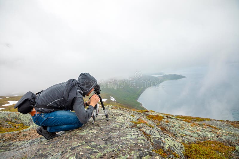 Jonge mens die op Panorama van aardmening kijken met fjord en bergen in wolken, Noorwegen stock afbeeldingen Jonge mens die op Panorama van aardmening kijken met fjord en bergen in wolken, Noorwegen stock afbeeldingen