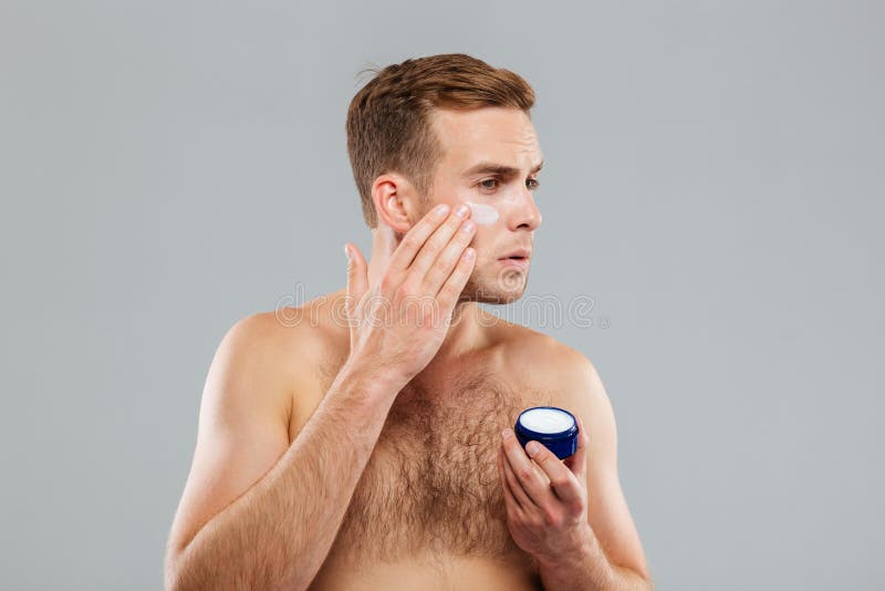 Jonge mens die roomlotion op gezicht zetten stock afbeeldingen Jonge mens die roomlotion op gezicht zetten stock afbeeldingen