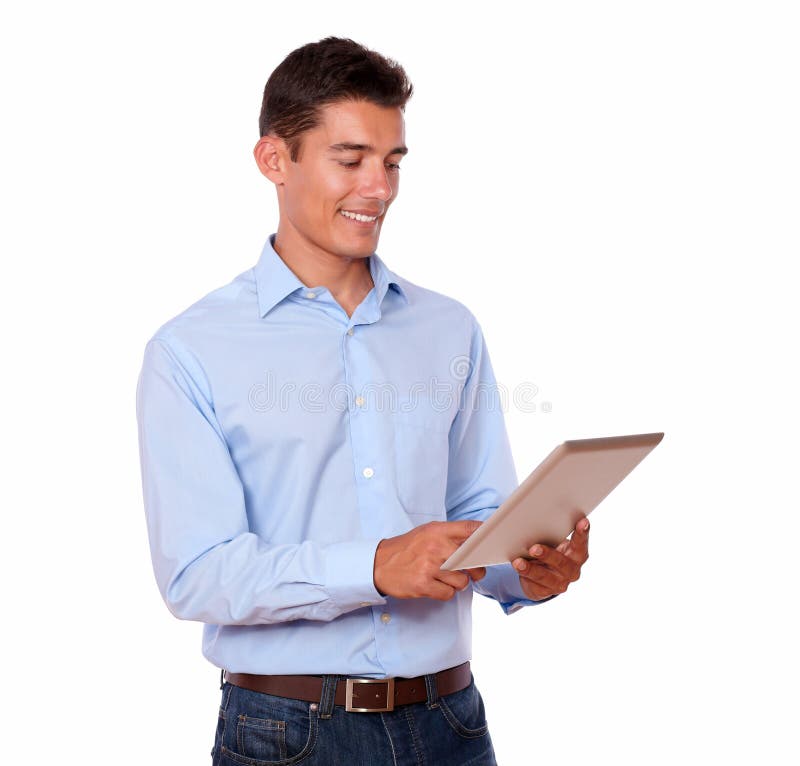 A portrait of a young man standing and smiling while looking at his tablet pc on isolated background. A portrait of a young man standing and smiling while looking at his tablet pc on isolated background