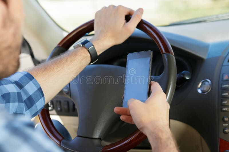 Jonge mens die telefoon met behulp van terwijl het zitten in de auto stock afbeelding Jonge mens die telefoon met behulp van terwijl het zitten in de auto stock afbeelding
