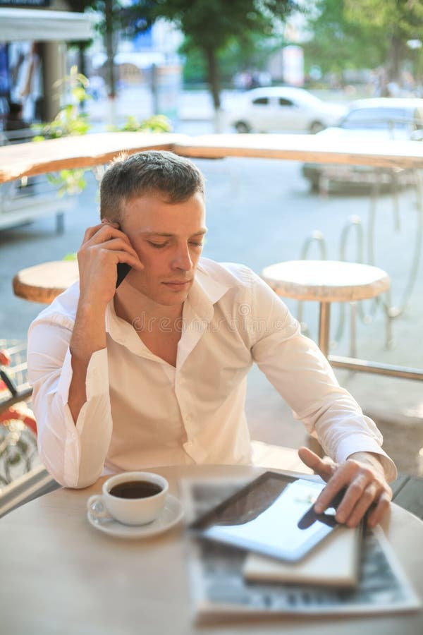Jonge mens het drinken koffie in koffie en het gebruiken van telefoon stock afbeeldingen Jonge mens het drinken koffie in koffie en het gebruiken van telefoon stock afbeeldingen