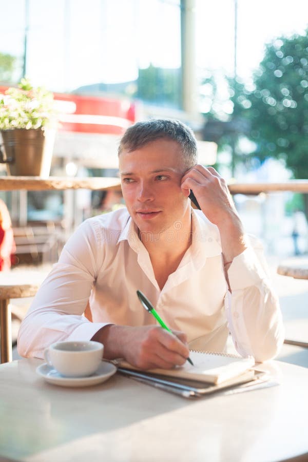 Jonge mens het drinken koffie in koffie en het gebruiken van telefoon royalty-vrije stock afbeeldingen Jonge mens het drinken koffie in koffie en het gebruiken van telefoon royalty-vrije stock afbeeldingen
