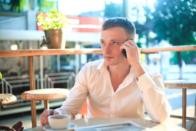 Jonge mens het drinken koffie in koffie en het gebruiken van telefoon stock foto Jonge mens het drinken koffie in koffie en het gebruiken van telefoon stock foto