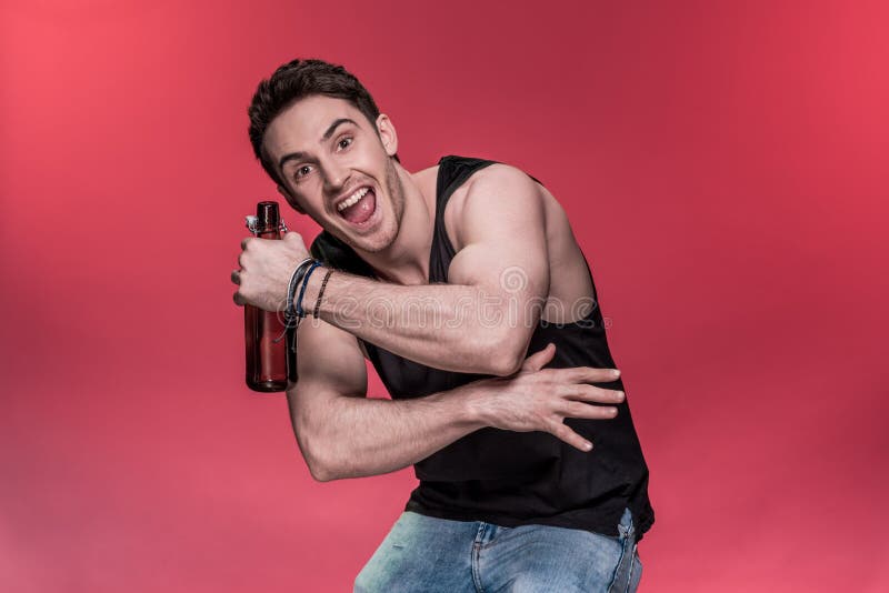 Jonge mens het gesturing met bierfles en het glimlachen bij camera royalty-vrije stock afbeeldingen Jonge mens het gesturing met bierfles en het glimlachen bij camera royalty-vrije stock afbeeldingen