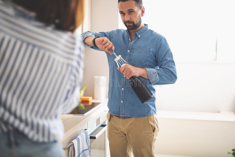 Jonge mens het openen fles wijn terwijl het bekijken dame royalty-vrije stock afbeeldingen Jonge mens het openen fles wijn terwijl het bekijken dame royalty-vrije stock afbeeldingen