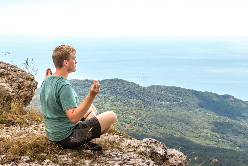 Jonge mens het praktizeren de yoga stelt zitting op de rotsachtige piek De mens doet meditatie en het genieten van van mening royalty-vrije stock afbeeldingen Jonge mens het praktizeren de yoga stelt zitting op de rotsachtige piek De mens doet meditatie en het genieten van van mening royalty-vrije stock afbeeldingen