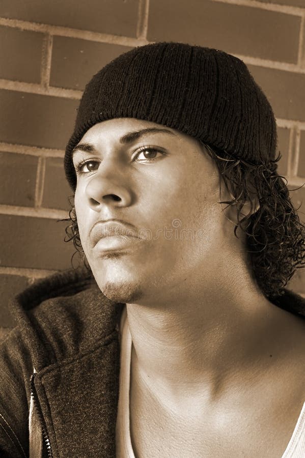 Young rapper with hat in front of brick wall. Young rapper with hat in front of brick wall