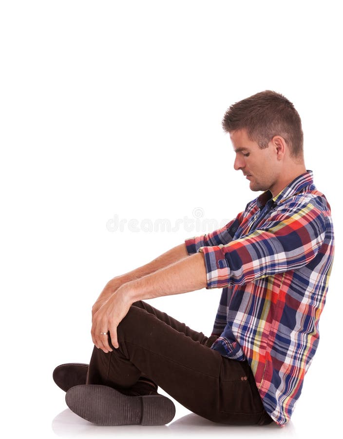 Side view of a casual cross legged young man looking down and holding his palms on his knees, on white. Side view of a casual cross legged young man looking down and holding his palms on his knees, on white