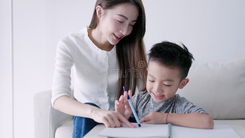 Jonge moeder die huiswerk controleert en kinderen helpt thuis te studeren