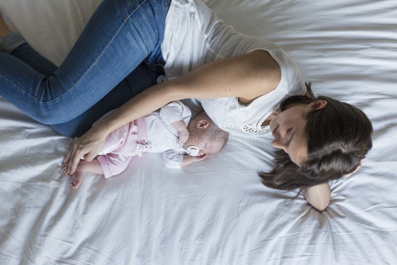 jonge moeder die op bed thuis met haar babymeisje liggen Familie en liefdeconcept stock foto's jonge moeder die op bed thuis met haar babymeisje liggen Familie en liefdeconcept stock foto's