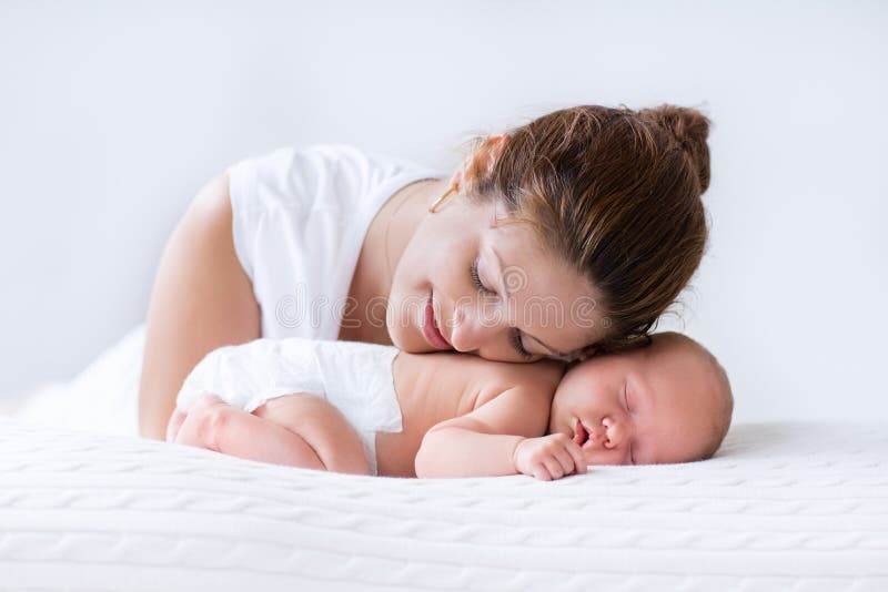 Jonge moeder en pasgeboren baby in witte slaapkamer