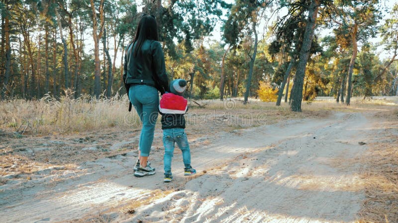 Jonge moeder loopt met een kleine zoon in het herfstbos