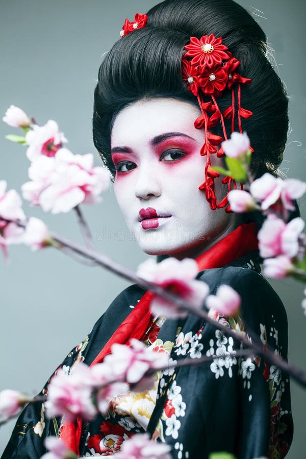 Jonge mooie geisha in zwarte kimono onder sakura, Aziatische ethnoclose-up royalty-vrije stock fotografie Jonge mooie geisha in zwarte kimono onder sakura, Aziatische ethnoclose-up royalty-vrije stock fotografie