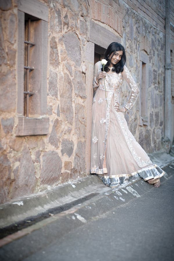 Jonge mooie Indische Vrouw die tegen steenmuur zich in openlucht bevinden royalty-vrije stock fotografie Jonge mooie Indische Vrouw die tegen steenmuur zich in openlucht bevinden royalty-vrije stock fotografie