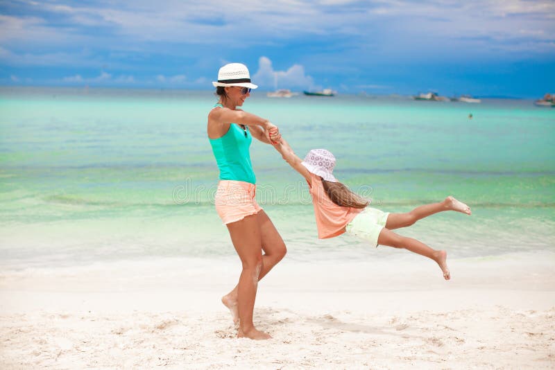 Een jonge, mooie moeder en haar schattige dochtertje hebben plezier op een tropisch strand. Er is een toestemmingsformulier aan de royalty-vrije stock afbeeldingen