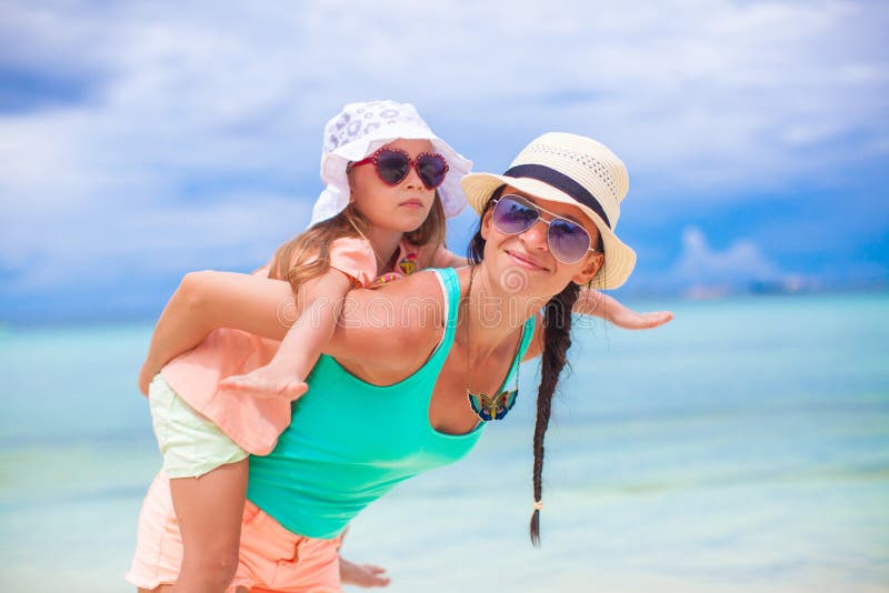Een jonge, mooie moeder en haar schattige dochtertje hebben plezier op een tropisch strand. Bij deze afbeelding is een toestemming royalty-vrije stock afbeelding