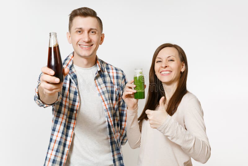 Jonge mooie paarman en vrouw die groene die detox houden smoothies, kola in glasfles op witte achtergrond wordt geïsoleerd