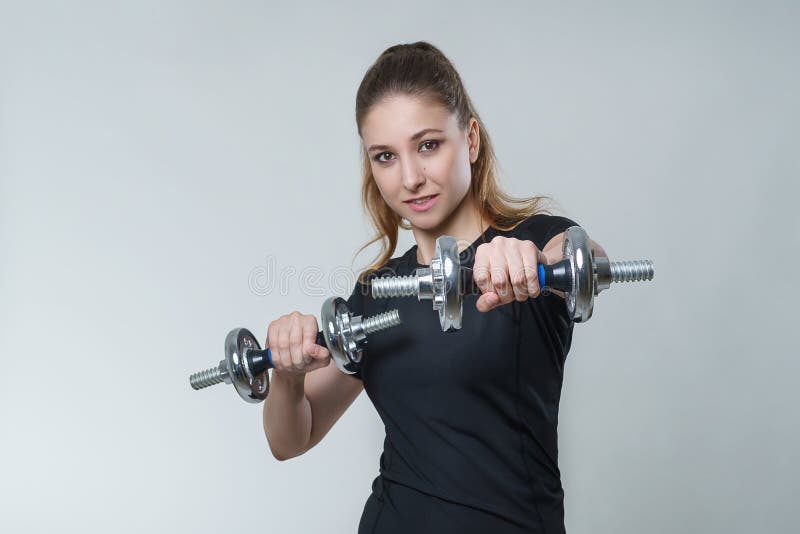 Jonge mooie sexy vrouw met donkerbruin haar in een zwarte t-shirt met metaaldomoren, portretfitness sportfoto stock foto Jonge mooie sexy vrouw met donkerbruin haar in een zwarte t-shirt met metaaldomoren, portretfitness sportfoto stock foto