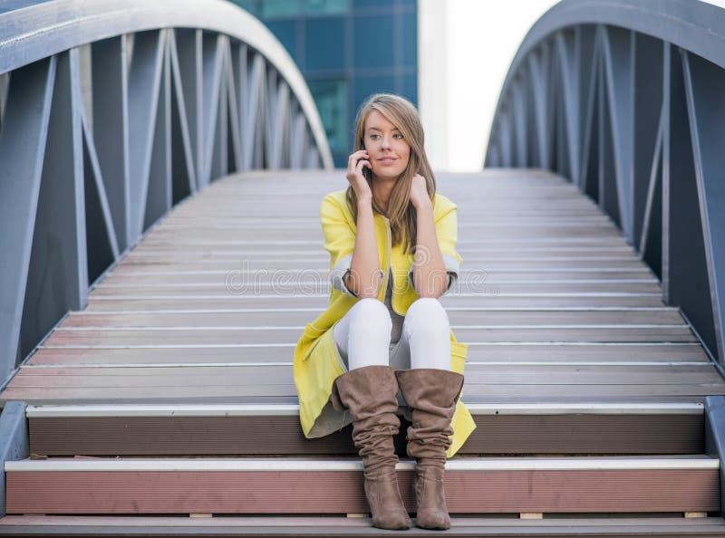 Jonge mooie vrouw die bij cellulaire telefoon op Brug spreken - vrouw die een gesprek hebben bij smartphone royalty-vrije stock fotografie Jonge mooie vrouw die bij cellulaire telefoon op Brug spreken - vrouw die een gesprek hebben bij smartphone royalty-vrije stock fotografie