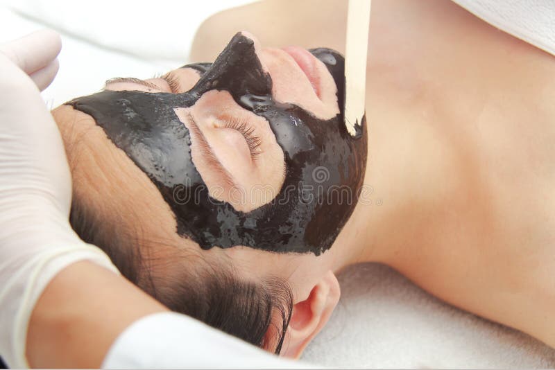 Young beautiful woman applying black charcoal facial mask. Skin care, beauty treatments. Spa treatments and care of the cats in the beauty salon. Young beautiful woman applying black charcoal facial mask. Skin care, beauty treatments. Spa treatments and care of the cats in the beauty salon.