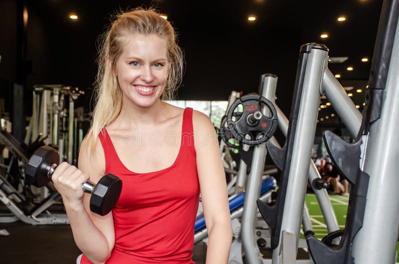Jonge, mooie vrouw die oefeningen doet om de dommel op te tillen in de gymzaal Glad glimlachend meisje geniet van haar trainingsp stock foto's Jonge, mooie vrouw die oefeningen doet om de dommel op te tillen in de gymzaal Glad glimlachend meisje geniet van haar trainingsp stock foto's