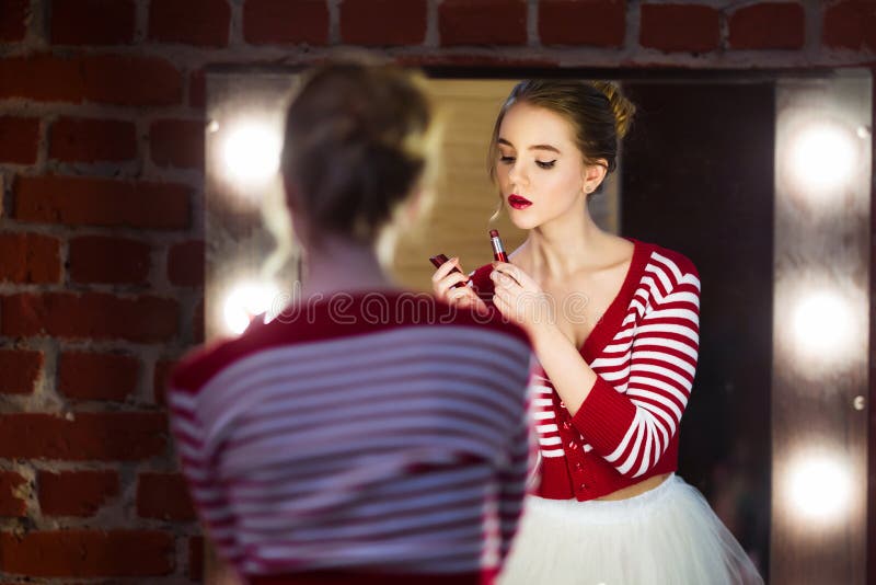 Jonge mooie vrouw die rode lippenstift toepassen die spiegel bekijken royalty-vrije stock foto Jonge mooie vrouw die rode lippenstift toepassen die spiegel bekijken royalty-vrije stock foto