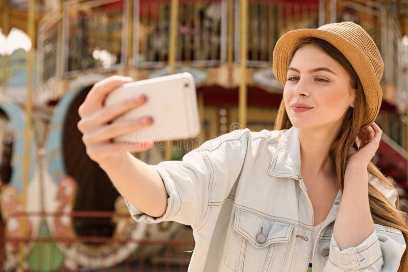 Jonge mooie vrouw die selfie dichtbij carrousel in park nemen stock afbeelding Jonge mooie vrouw die selfie dichtbij carrousel in park nemen stock afbeelding