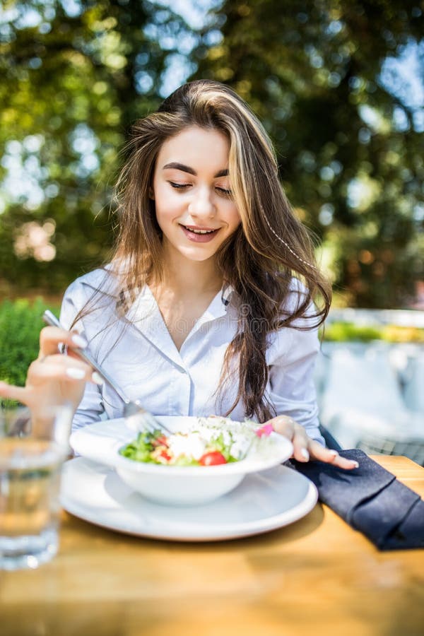 Jonge mooie Vrouw die smakelijke salade in koffie in openlucht eten royalty-vrije stock foto's Jonge mooie Vrouw die smakelijke salade in koffie in openlucht eten royalty-vrije stock foto's