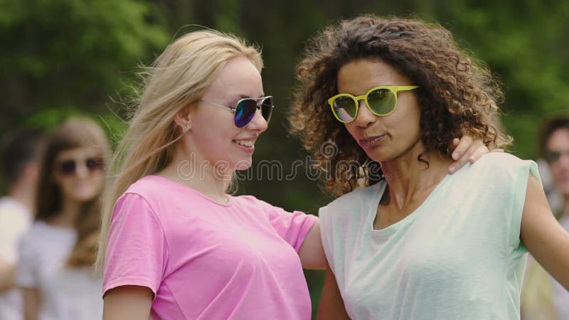 Jonge mooie vrouwen in gele zonnebril die met vrienden, ontspanning in park dansen