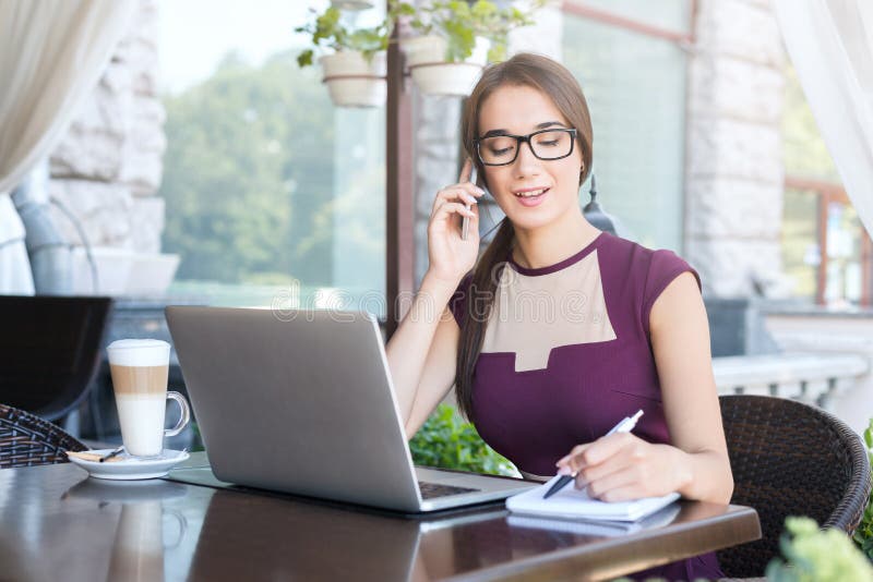 Jonge onderneemster die op telefoon in koffie spreken royalty-vrije stock foto Jonge onderneemster die op telefoon in koffie spreken royalty-vrije stock foto