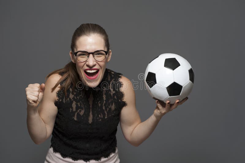 Jonge opgewekte van de de ventilatorholding van de vrouwenvoetbal het voetbalbal in handen stock foto Jonge opgewekte van de de ventilatorholding van de vrouwenvoetbal het voetbalbal in handen stock foto