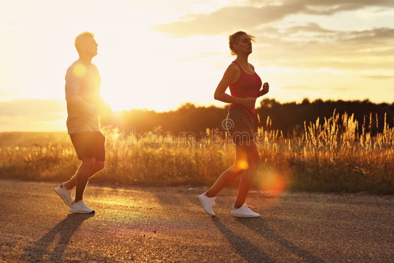 Jonge paarjogging in suberbs na zonsondergang stock afbeelding Jonge paarjogging in suberbs na zonsondergang stock afbeelding