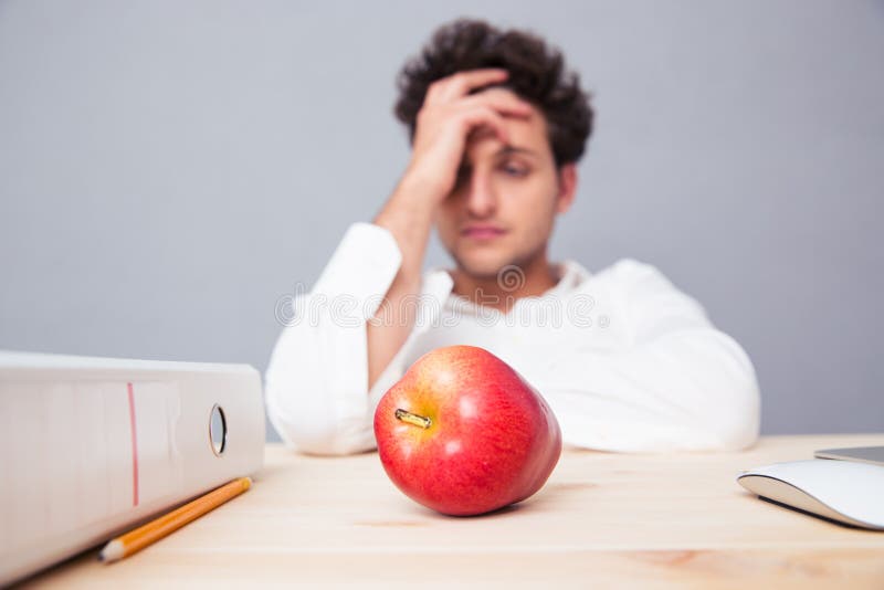 Jonge peinzende zakenmanzitting bij de lijst stock foto Jonge peinzende zakenmanzitting bij de lijst stock foto