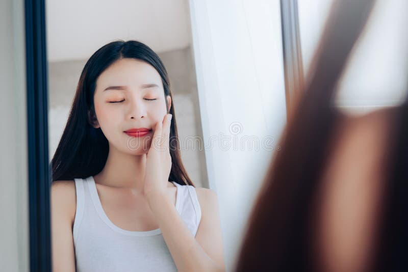 Jonge Schoonheids Aziatische Vrouw die het Duidelijke Gezicht Skincare bekijkt van de Spiegelcontrole stock fotografie Jonge Schoonheids Aziatische Vrouw die het Duidelijke Gezicht Skincare bekijkt van de Spiegelcontrole stock fotografie