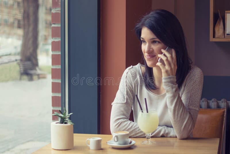 Jonge smartphone van het vrouwengebruik bij koffie royalty-vrije stock afbeelding Jonge smartphone van het vrouwengebruik bij koffie royalty-vrije stock afbeelding