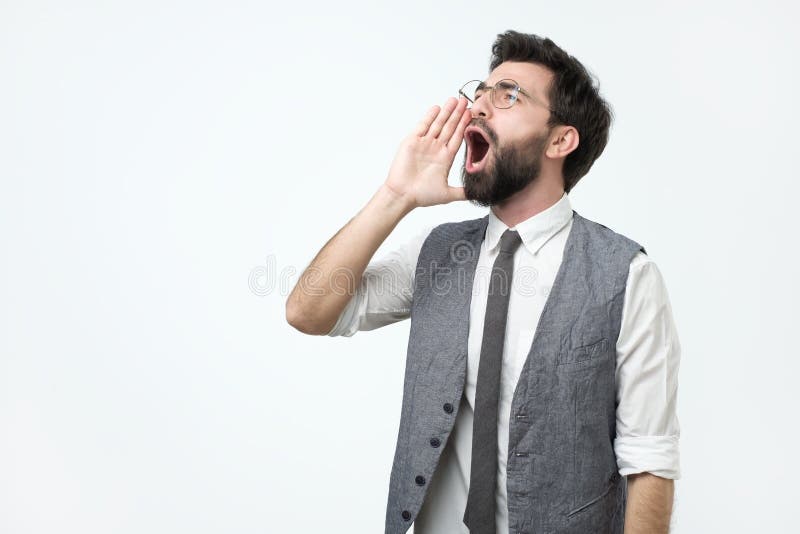 Jonge Spaanse volwassen mens met en baard die luid aan kant met hand op mond schreeuwen gillen stock foto's Jonge Spaanse volwassen mens met en baard die luid aan kant met hand op mond schreeuwen gillen stock foto's
