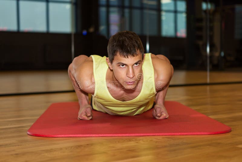 jonge spiermens die duw UPS in gymnastiek doen stock afbeelding jonge spiermens die duw UPS in gymnastiek doen stock afbeelding