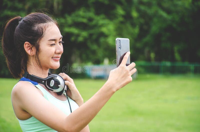 Jonge Sportieve Vrouw die een Selfie nemen bij Park Zij bekijkt Smartphone, heeft zij een Smartphonehouder op haar Wapen en luist stock foto's Jonge Sportieve Vrouw die een Selfie nemen bij Park Zij bekijkt Smartphone, heeft zij een Smartphonehouder op haar Wapen en luist stock foto's