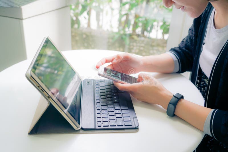 Jonge studentenvrouwen die slimme band wat betreft slimme telefoon dragen terwijl het gebruiken van tabletcomputer stock foto Jonge studentenvrouwen die slimme band wat betreft slimme telefoon dragen terwijl het gebruiken van tabletcomputer stock foto