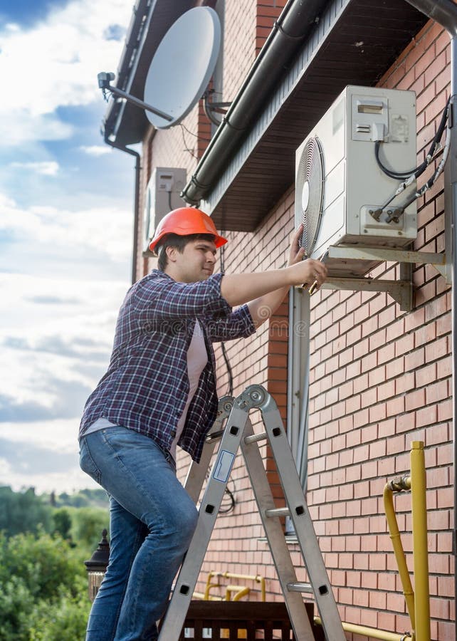 Jonge technicus die buitenairconditioningseenheid herstellen royalty-vrije stock afbeeldingen Jonge technicus die buitenairconditioningseenheid herstellen royalty-vrije stock afbeeldingen