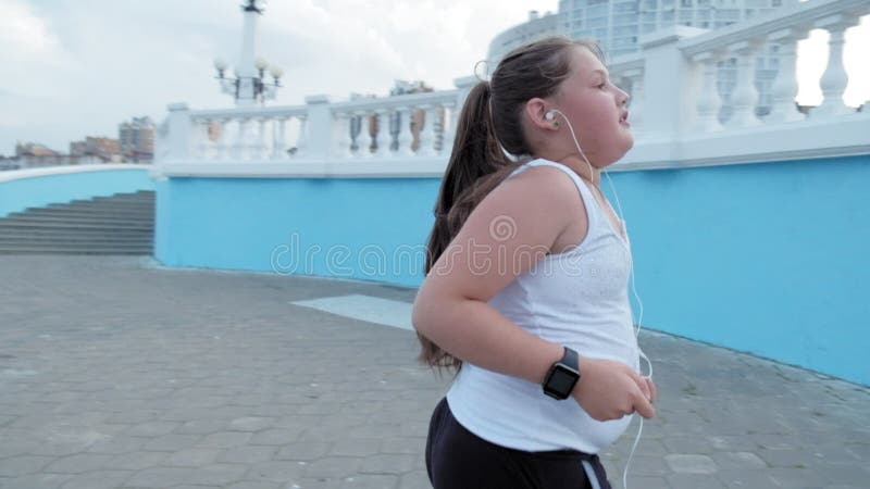 Jonge vette meisjes leeglopende treden, die gewicht afwerpen, die aan muziek in super hoofdtelefoonsconcept luisteren gezonde lev