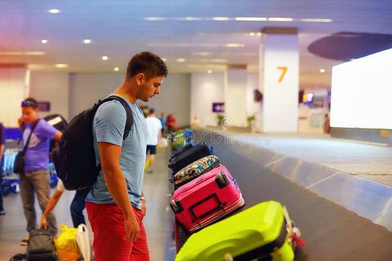 Jonge volwassen mens, passagier die op bagage in luchthaventerminal wachten royalty-vrije stock foto Jonge volwassen mens, passagier die op bagage in luchthaventerminal wachten royalty-vrije stock foto
