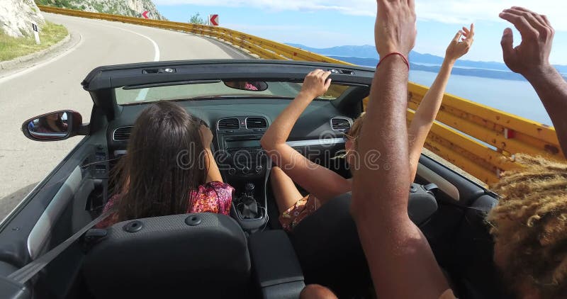 Jonge vrienden die van het kustlandschap berijden in convertibel bij het winden van weg genieten